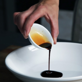 Pouring a dark brown sauce in a ceramic bowl