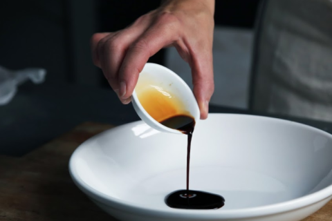 Pouring a dark brown sauce in a ceramic bowl